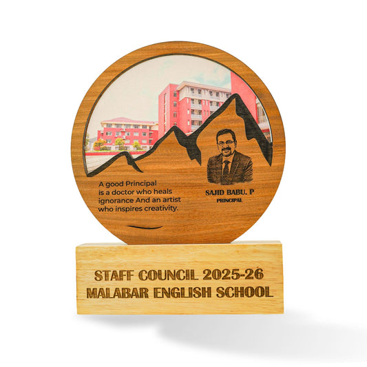 A custom wooden school staff council award plaque on a light wood base. The round wooden top features an engraved portrait of Principal Said Babu, a mountain silhouette, a school building illustration, and a quote.